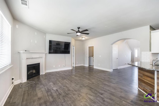 unfurnished living room with ceiling fan and dark wood-type flooring