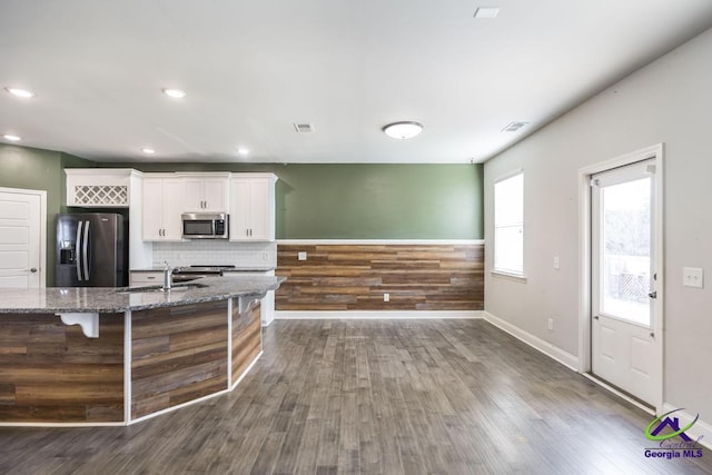 kitchen featuring sink, white cabinetry, a kitchen breakfast bar, dark stone counters, and appliances with stainless steel finishes