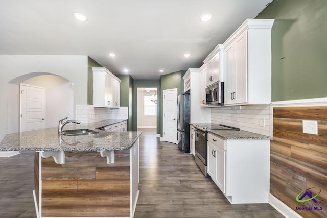 kitchen with a kitchen breakfast bar, appliances with stainless steel finishes, sink, white cabinetry, and stone countertops