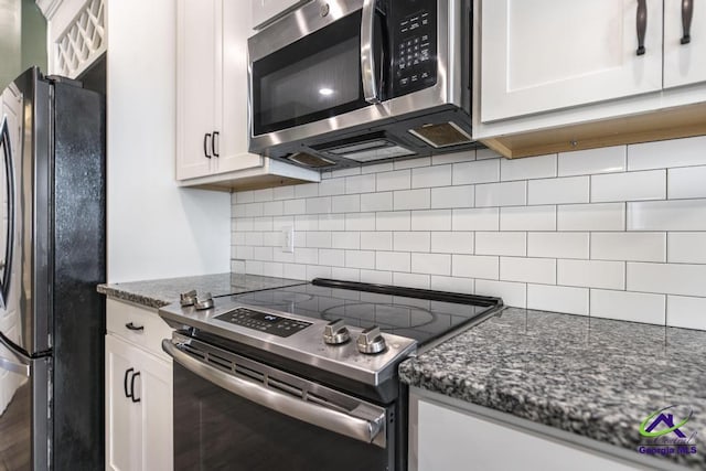 kitchen with stainless steel appliances, dark stone counters, and white cabinetry