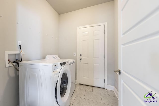 clothes washing area with washing machine and clothes dryer and light tile patterned floors