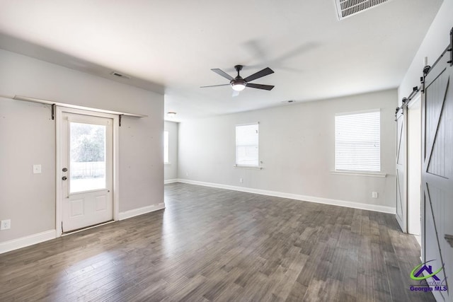 foyer with ceiling fan, dark hardwood / wood-style flooring, a barn door, and plenty of natural light