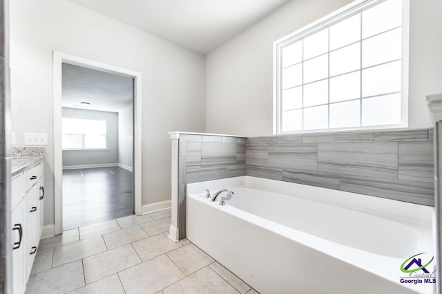 bathroom featuring a tub to relax in, tile patterned flooring, and vanity