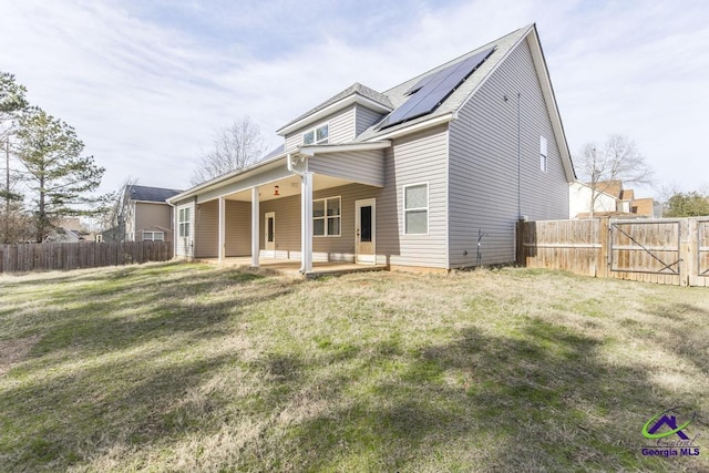 view of front of property featuring a patio, a front lawn, and solar panels