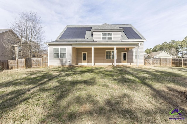 rear view of property with solar panels and a yard