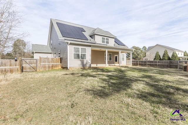 back of house featuring a lawn and solar panels