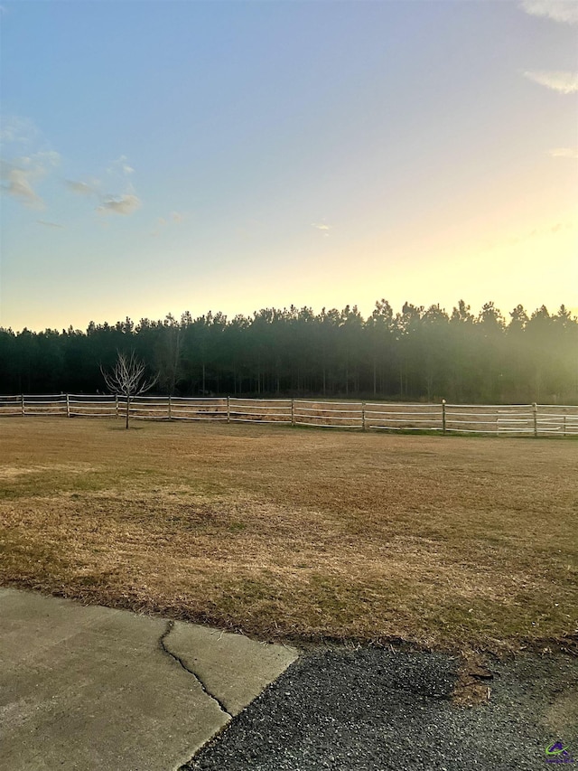 yard at dusk featuring a rural view