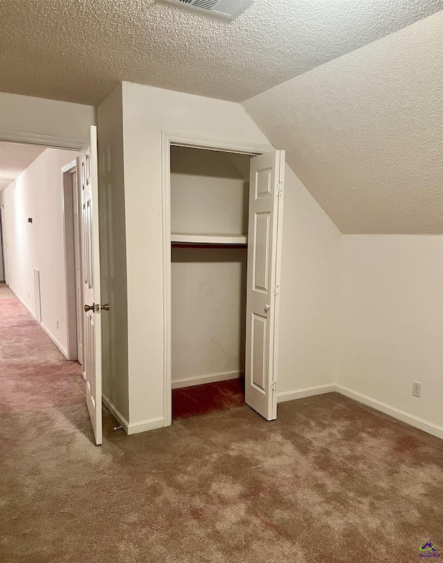 interior space with a textured ceiling, carpet, and lofted ceiling