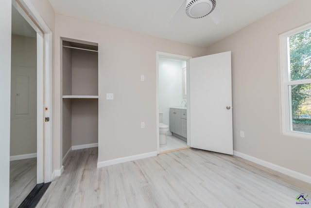 unfurnished bedroom featuring ensuite bathroom, light wood-type flooring, and a closet