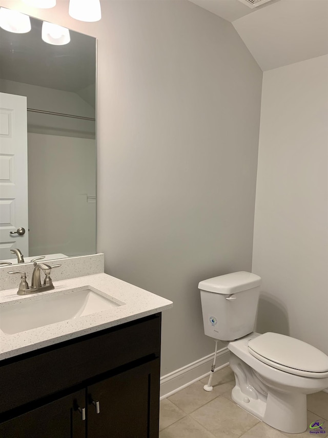 bathroom with toilet, vanity, tile patterned floors, and vaulted ceiling