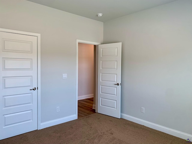 unfurnished bedroom with dark carpet and a closet