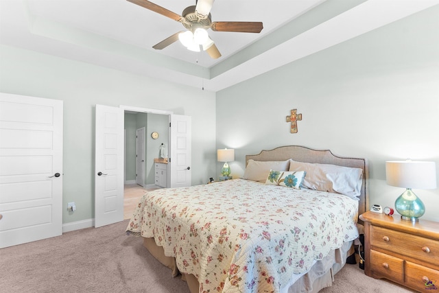 carpeted bedroom featuring ceiling fan and a raised ceiling