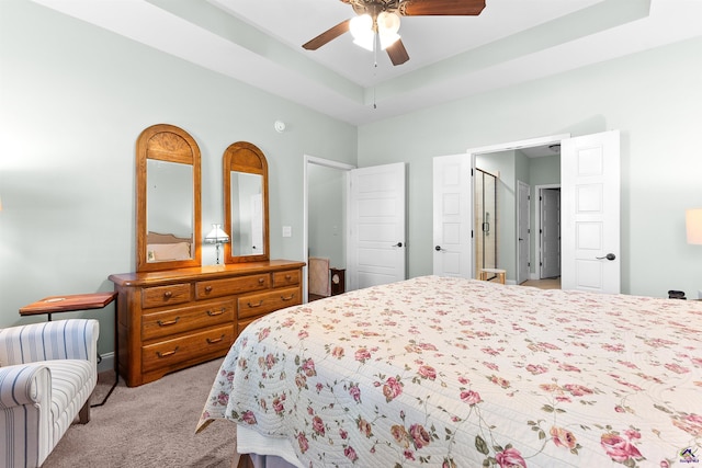 carpeted bedroom featuring ceiling fan and a tray ceiling