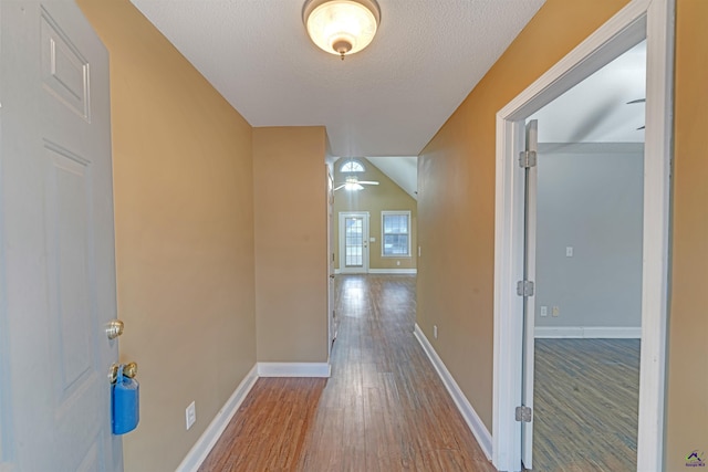 hall with lofted ceiling, a textured ceiling, and hardwood / wood-style flooring