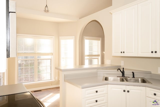 kitchen featuring a wealth of natural light, white cabinetry, pendant lighting, and sink