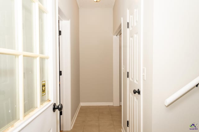 corridor featuring a textured ceiling and light tile patterned floors