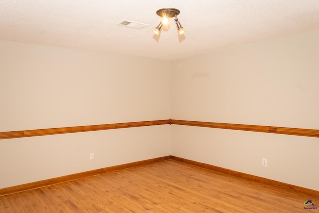 spare room featuring light hardwood / wood-style floors and an inviting chandelier