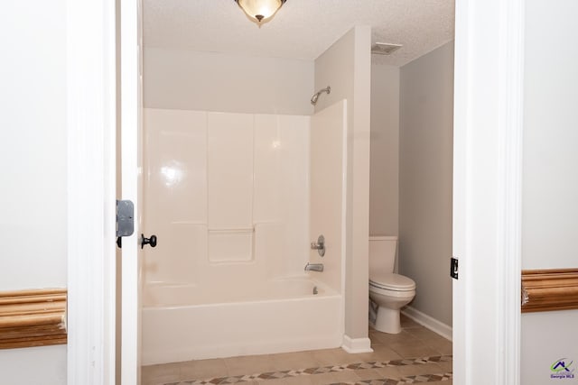 bathroom with a textured ceiling, tile patterned floors, toilet, and shower / washtub combination