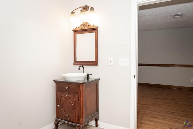 bathroom featuring a textured ceiling, hardwood / wood-style flooring, and vanity