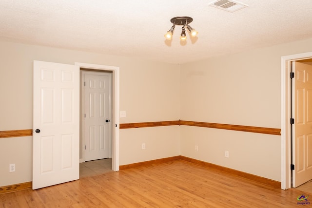 empty room featuring wood-type flooring and a textured ceiling