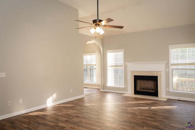 unfurnished living room featuring ceiling fan, hardwood / wood-style flooring, a premium fireplace, and a healthy amount of sunlight