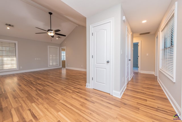 hallway with plenty of natural light, lofted ceiling with beams, and light wood-type flooring