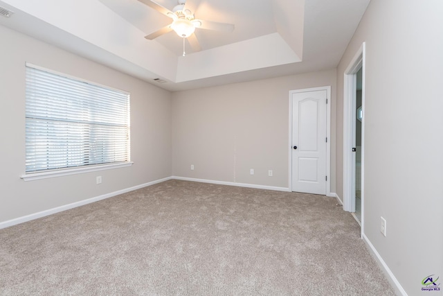 spare room with light carpet, ceiling fan, and a tray ceiling