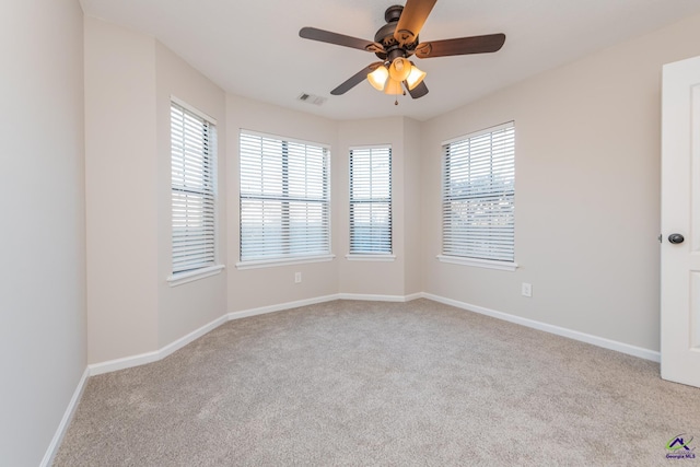 carpeted spare room featuring ceiling fan and a healthy amount of sunlight