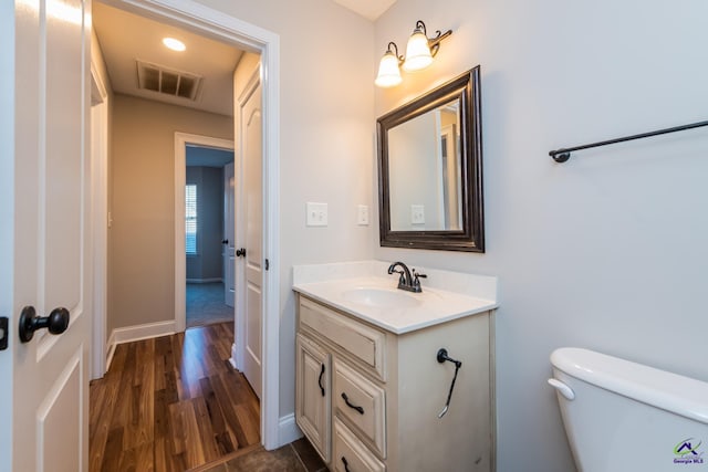 bathroom with hardwood / wood-style floors, toilet, and vanity