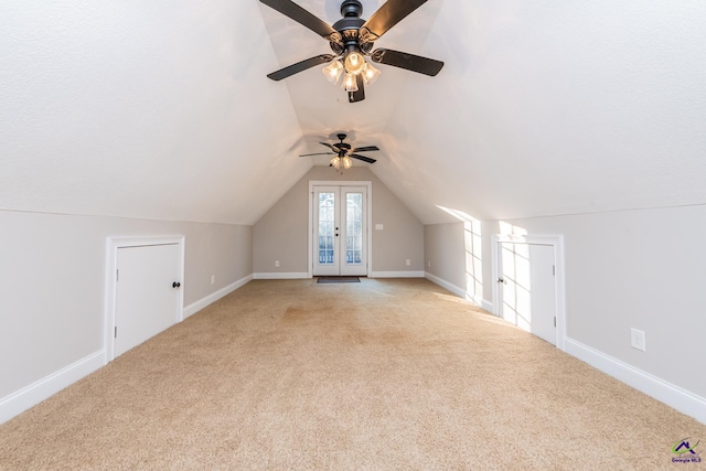 additional living space with ceiling fan, lofted ceiling, light colored carpet, and french doors