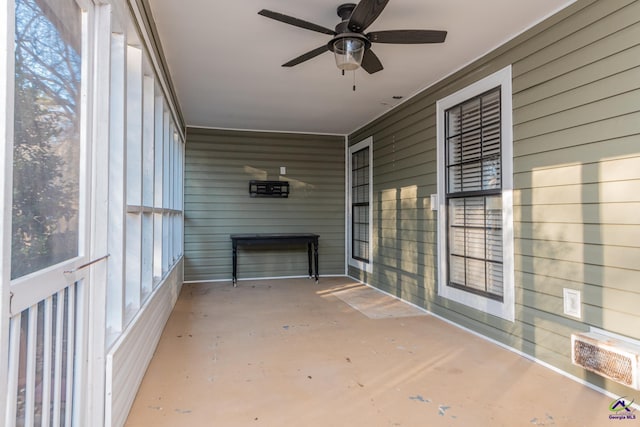 unfurnished sunroom featuring ceiling fan and a fireplace