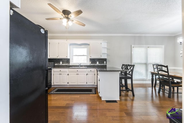 kitchen featuring a wealth of natural light, white cabinets, sink, and black fridge