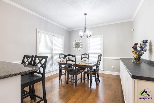 dining space featuring dark hardwood / wood-style flooring, an inviting chandelier, a textured ceiling, and ornamental molding