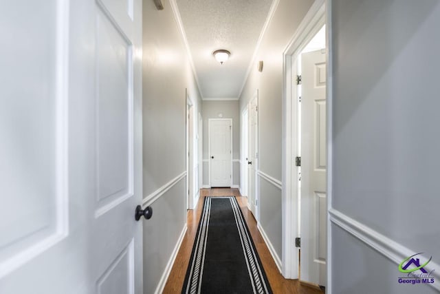 hall with wood-type flooring, a textured ceiling, and crown molding