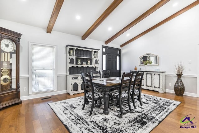 dining room with vaulted ceiling with beams and wood-type flooring