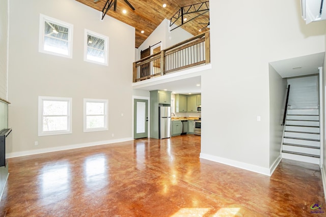 unfurnished living room featuring wooden ceiling, concrete flooring, and a towering ceiling