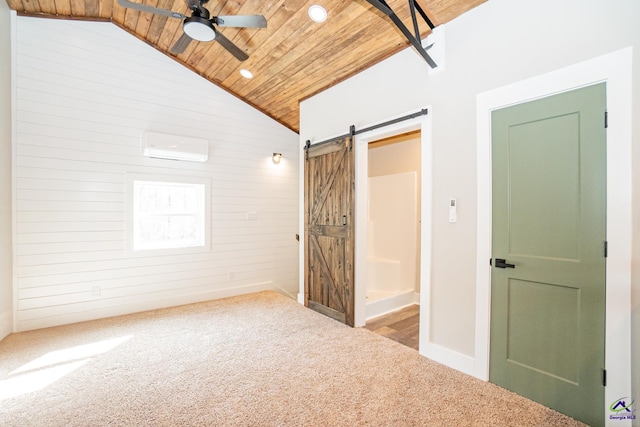 carpeted spare room with wood walls, a wall mounted AC, ceiling fan, wooden ceiling, and a barn door