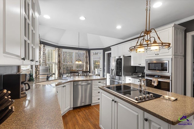 kitchen featuring vaulted ceiling, stainless steel appliances, white cabinets, and hanging light fixtures