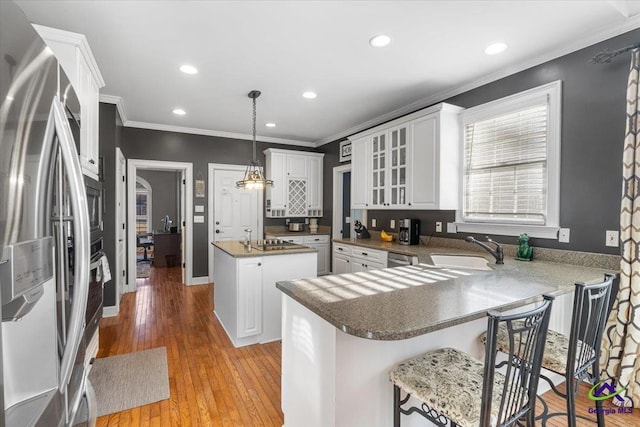 kitchen featuring pendant lighting, appliances with stainless steel finishes, a center island, sink, and kitchen peninsula