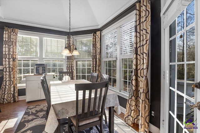 dining room featuring hardwood / wood-style flooring, lofted ceiling, crown molding, and a notable chandelier