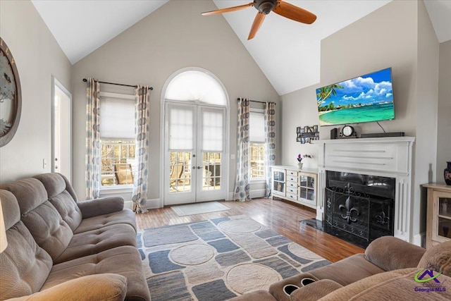 living room with hardwood / wood-style flooring, ceiling fan, french doors, and high vaulted ceiling