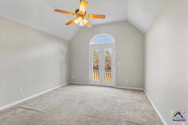 empty room featuring ceiling fan, light colored carpet, french doors, and vaulted ceiling