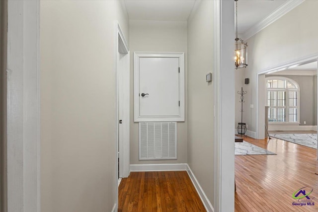 hall featuring dark hardwood / wood-style flooring, crown molding, and a notable chandelier