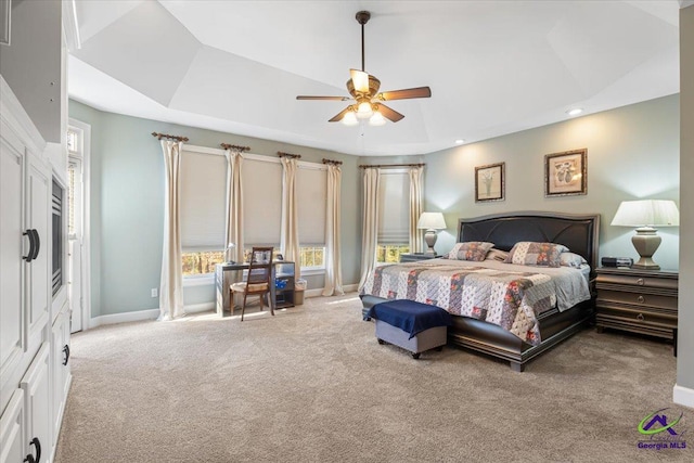 bedroom featuring ceiling fan, light carpet, and a raised ceiling