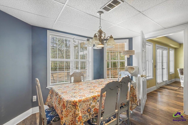 dining room featuring a drop ceiling, dark hardwood / wood-style flooring, and an inviting chandelier