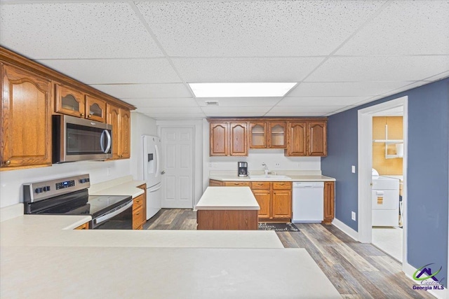 kitchen with appliances with stainless steel finishes, sink, dark wood-type flooring, a drop ceiling, and a center island