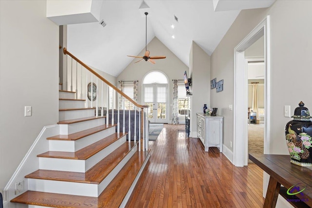 stairs with ceiling fan, hardwood / wood-style flooring, and a towering ceiling