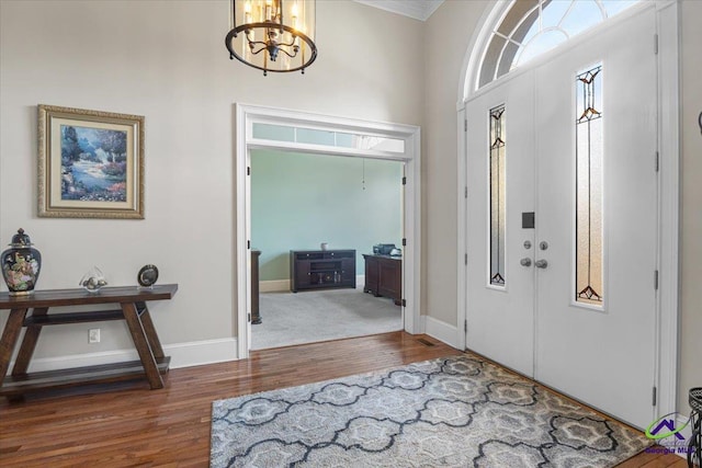 foyer featuring dark hardwood / wood-style floors, an inviting chandelier, and ornamental molding