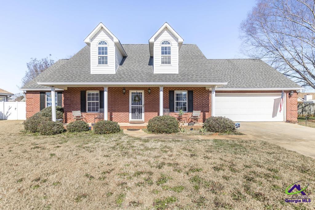 cape cod home with a front yard, a garage, and a porch