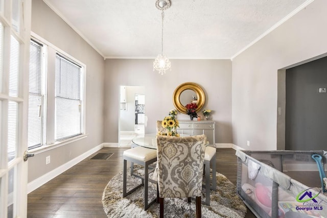 dining space with a textured ceiling, dark hardwood / wood-style flooring, crown molding, and a chandelier